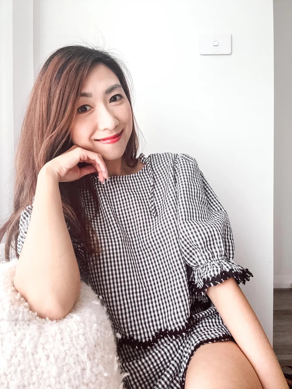 Jeannie Chow smiling, chin resting on her hand, in a black-and-white gingham top