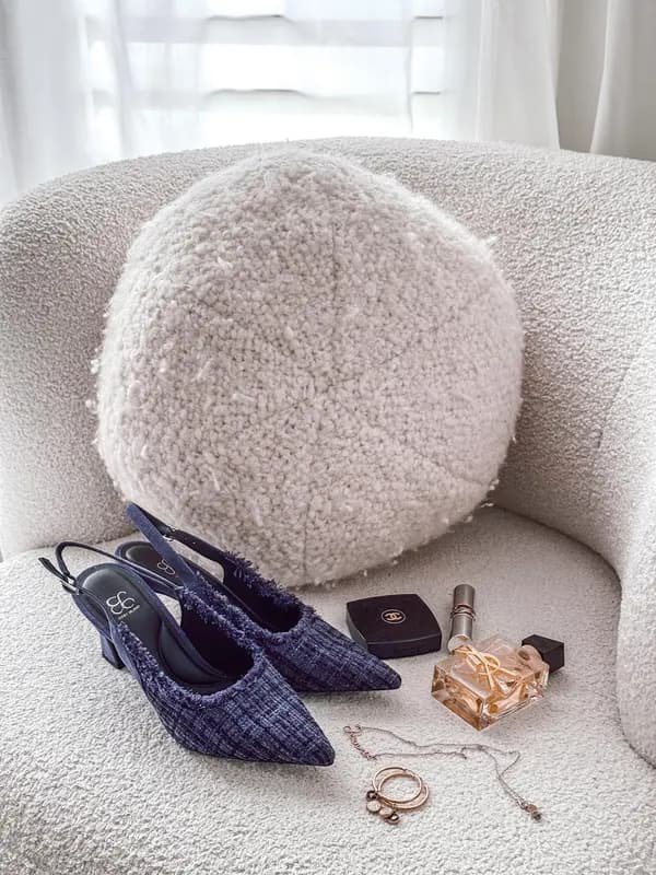 Tweed slingback heels, perfume and jewellery styled on a bouclé chair