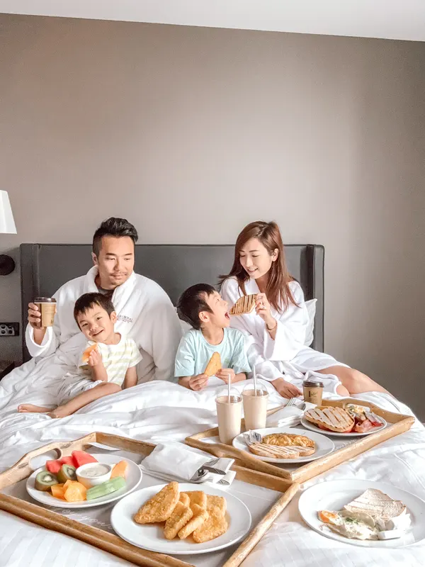 A family enjoying breakfast in bed in a hotel room