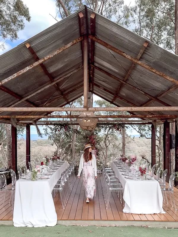 A long dining table set under a rustic open-air pavilion